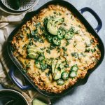 Green Chili Enchilada Cornbread Casserole garnished with sliced avocados and jalapeños.