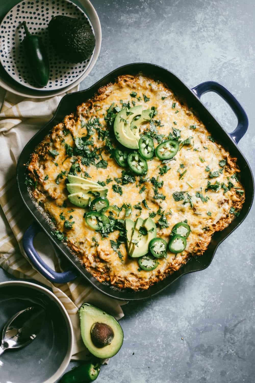 Green Chili Enchilada Cornbread Casserole garnished with sliced avocados and jalapeños.