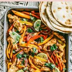 chili lime chicken and vegetables on a sheet pan with flour tortillas on the side