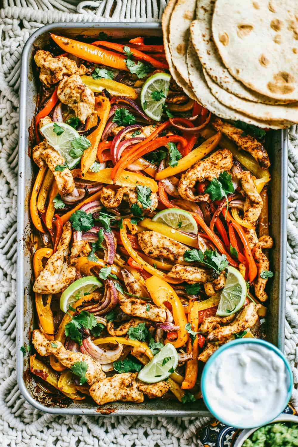 chili lime chicken and vegetables on a sheet pan with flour tortillas on the side