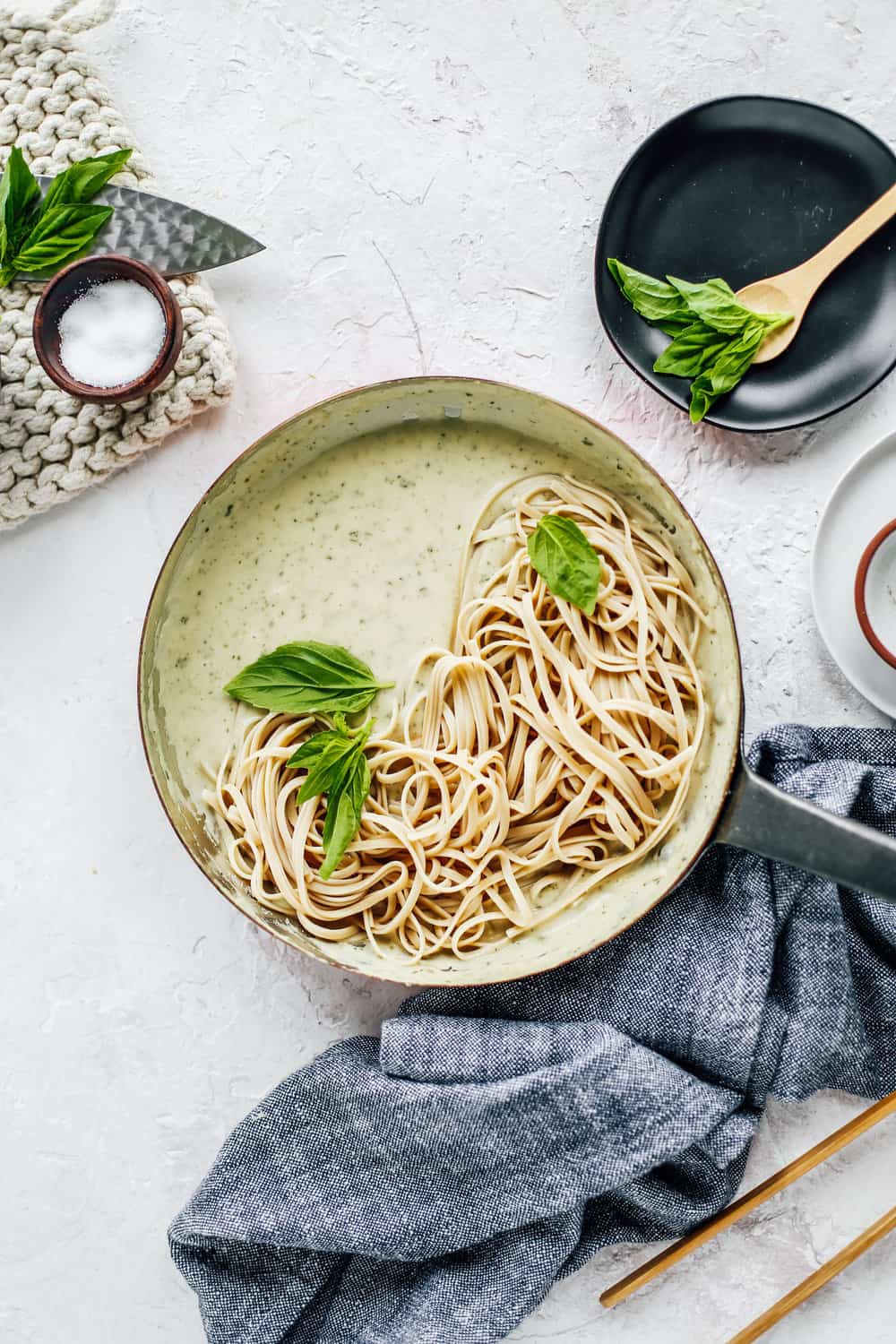 Skinny Fettuccine Pesto Alfredo in skillet with basil leaves and salt