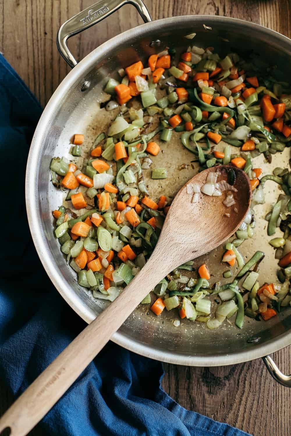 Diced carrots, celery, leeks, and onions in a saute pan. 