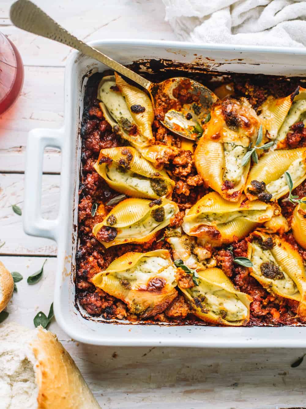 cheesy pesto stuffed shells with marinara sauce in white casserole dish