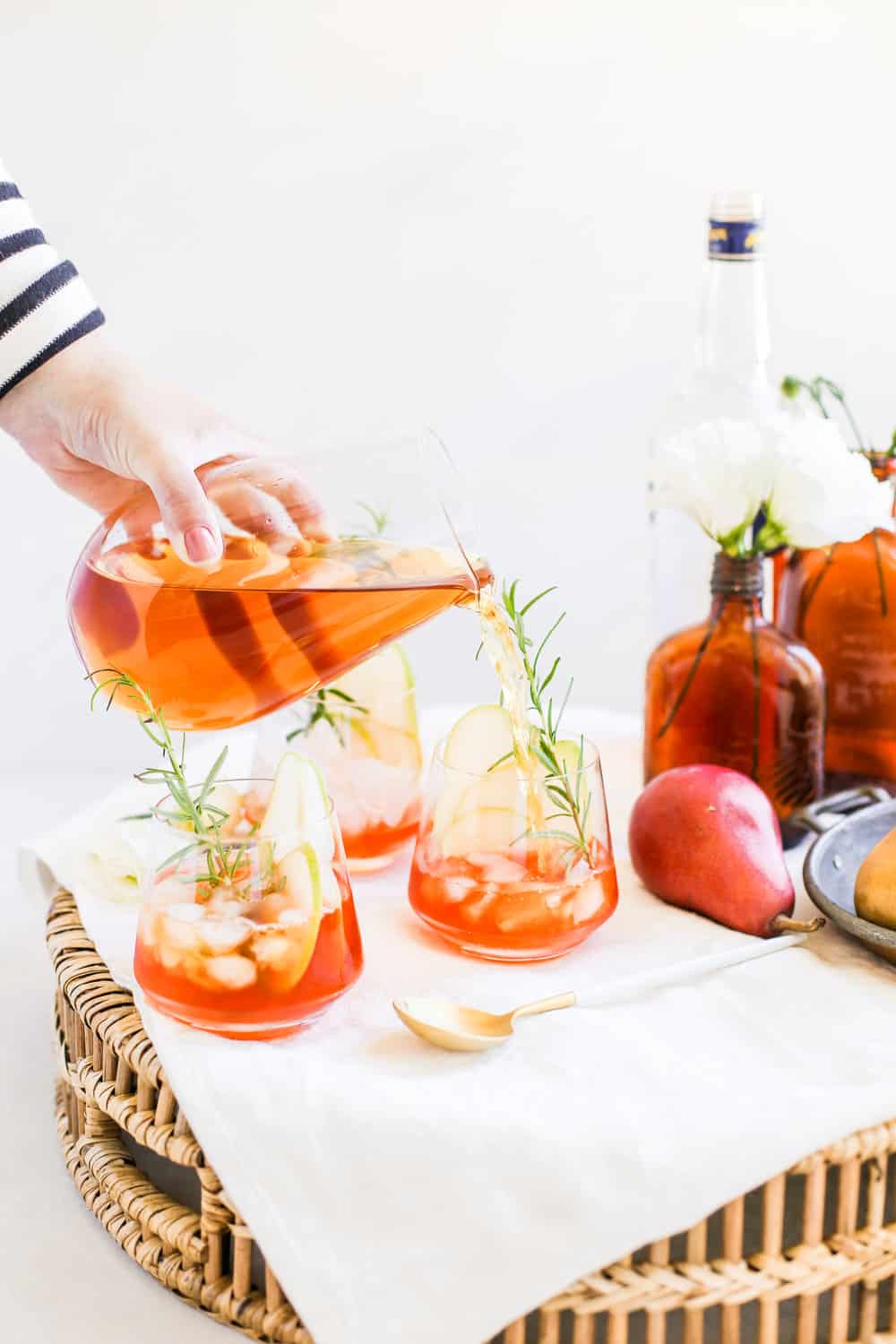 Apple juice being poured into a low clear glass on a serving tray. 