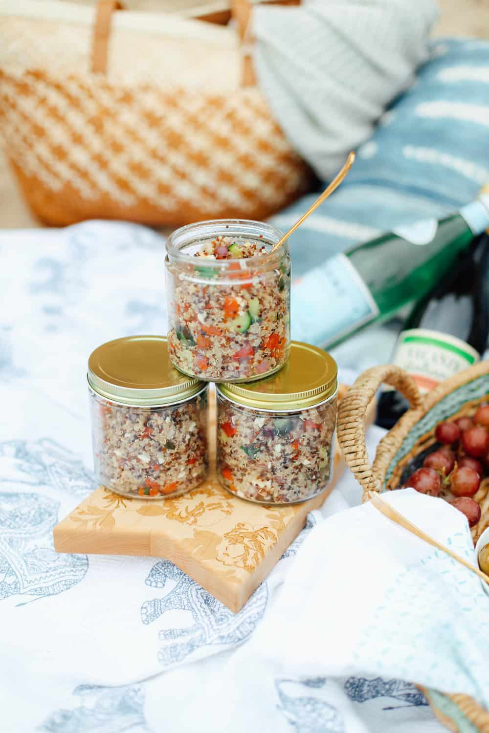 Lemon Quinoa Side Salad in three mason jars with gold lids on a wooden board on beach towels