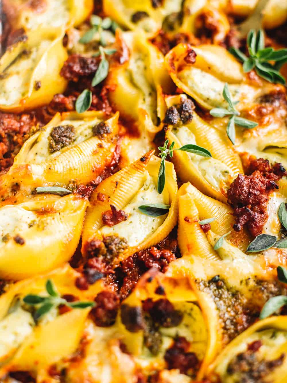 close-up of pesto stuffed shells in Italian sausage marinara sauce