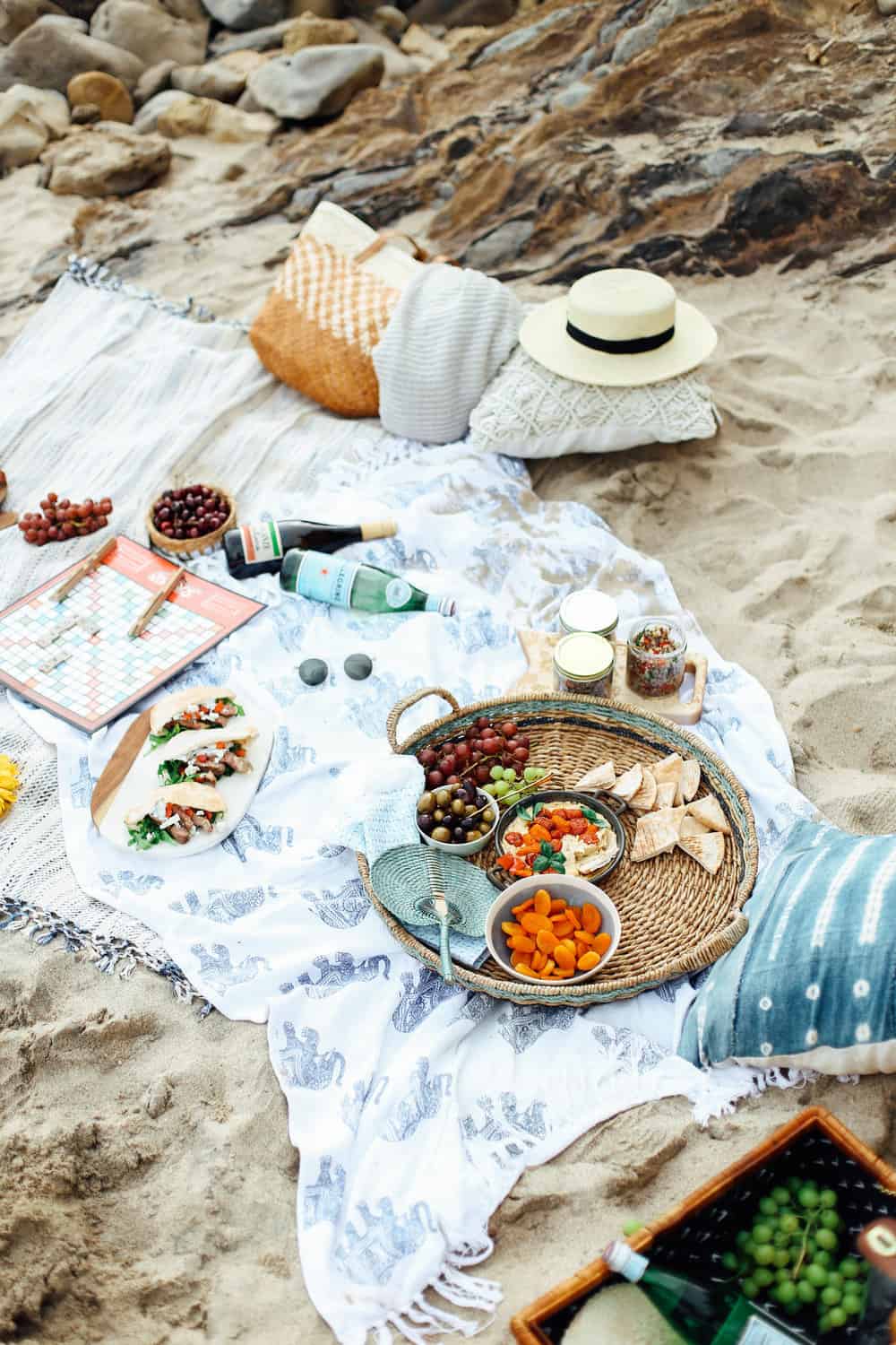 Mediterranean Beach Picnic food and drinks in a wicker basket on beach towels at the beach