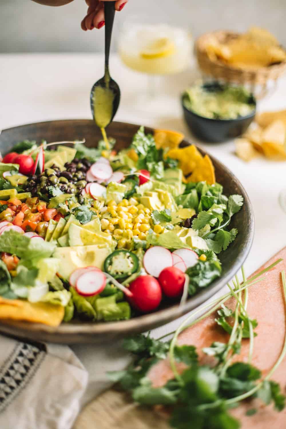 A big wooden bowl of a Chopped Tostada Salad with Avocado Cilantro Dressing