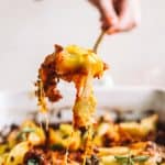 cheesy pesto stuffed shells being spooned out from casserole dish