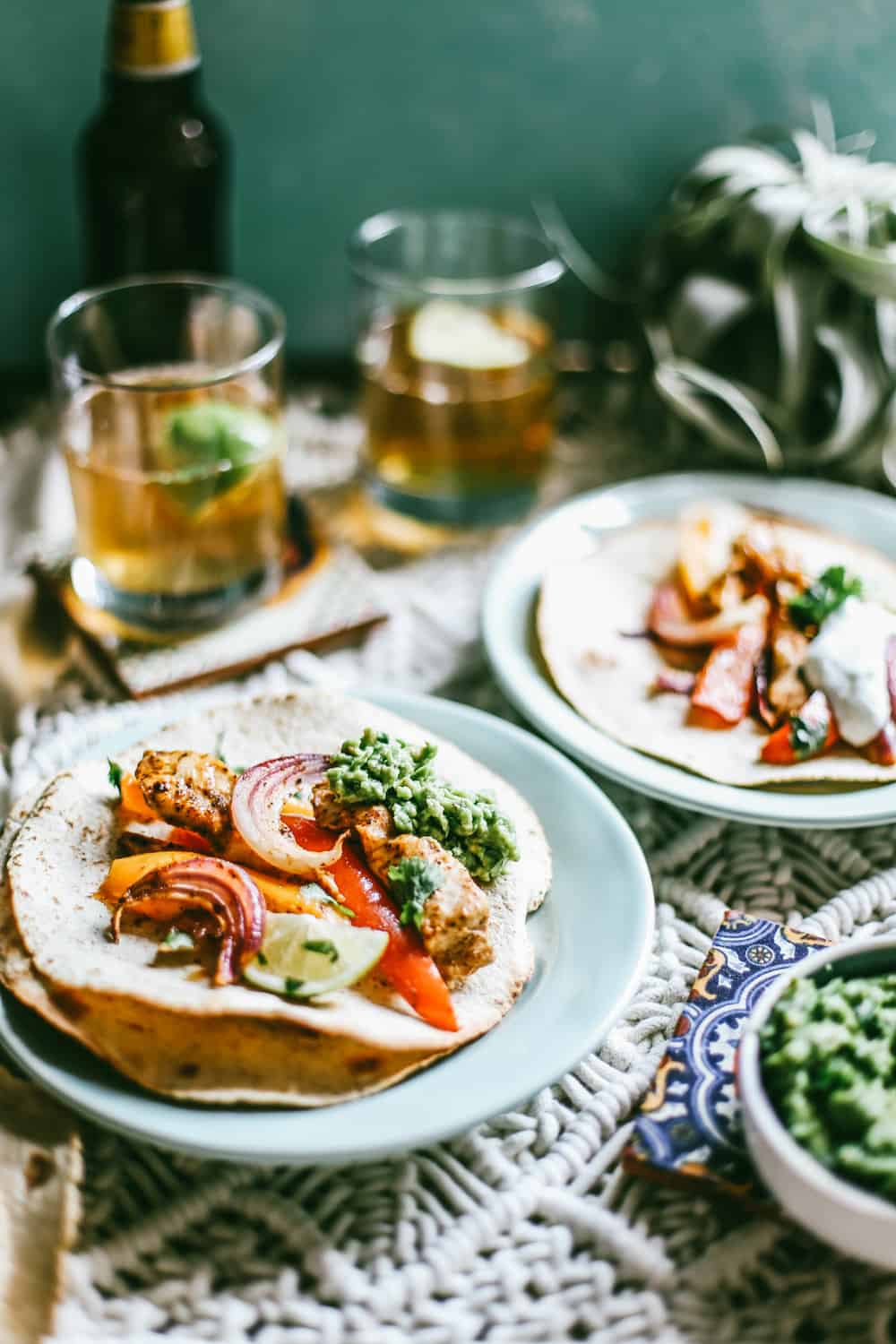 sheet pan chicken fajitas in flour tortillas on blue plate with glasses of beer