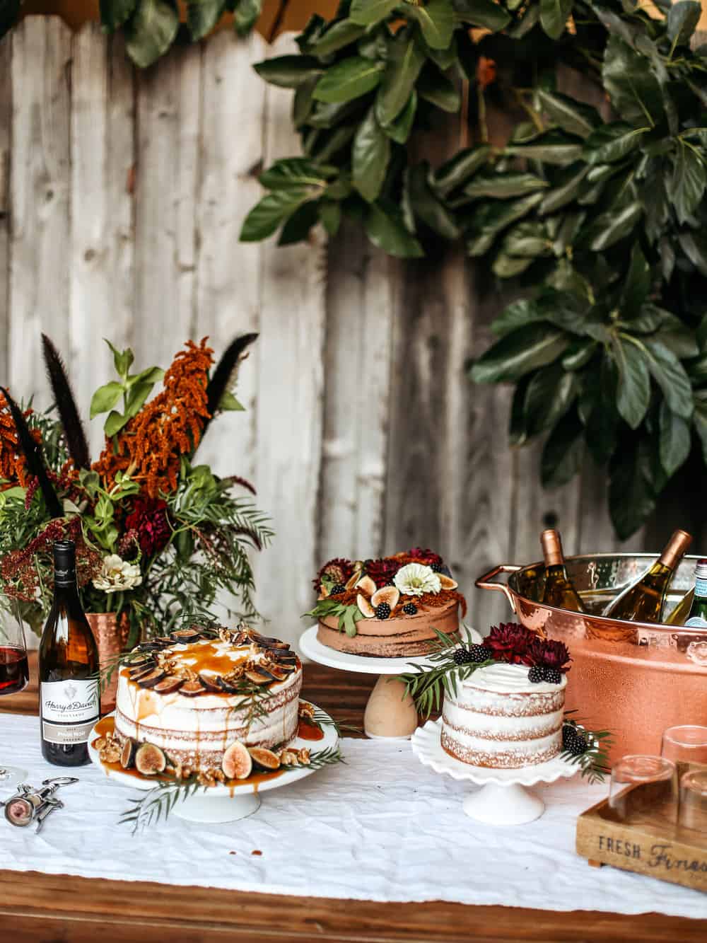 Mood and Dark tablescape with naked cakes topped with floral arrangements 