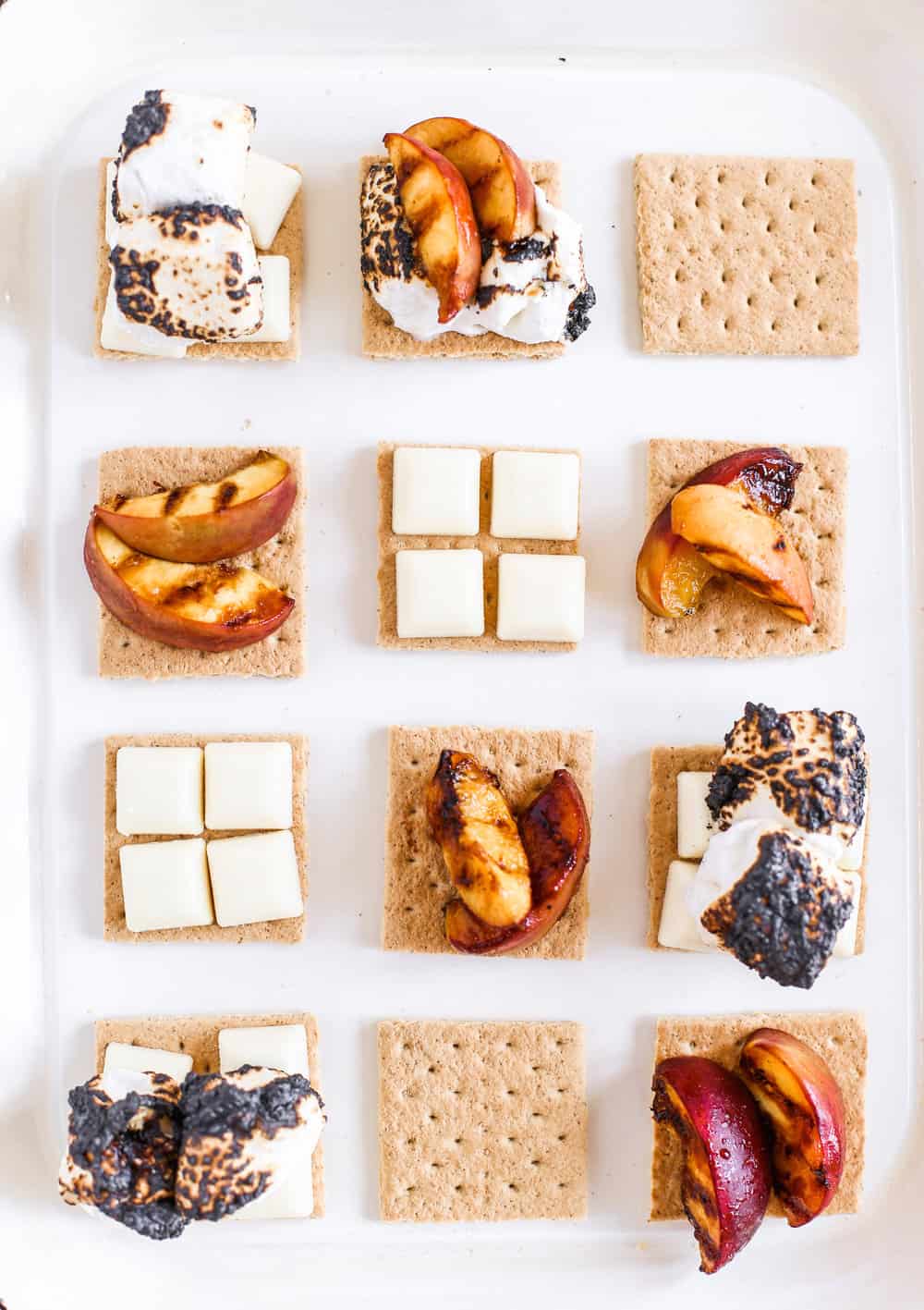 Overhead of prepped ingredients for Smeaches with graham crackers, white chocolate, grilled peaches, and toasted marshmallows