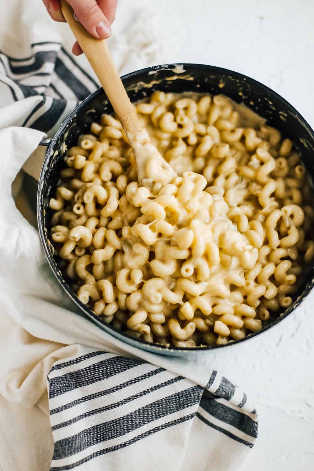 creamy macaroni and cheese in pot with wooden spoon