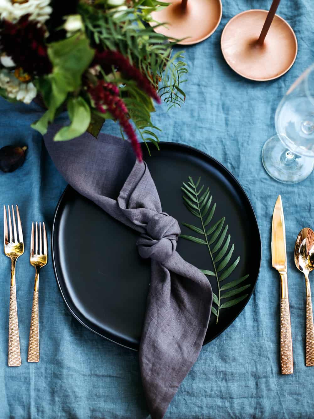 Moody and Dark tablescape with copper details, black plates, and deep purple linens. 