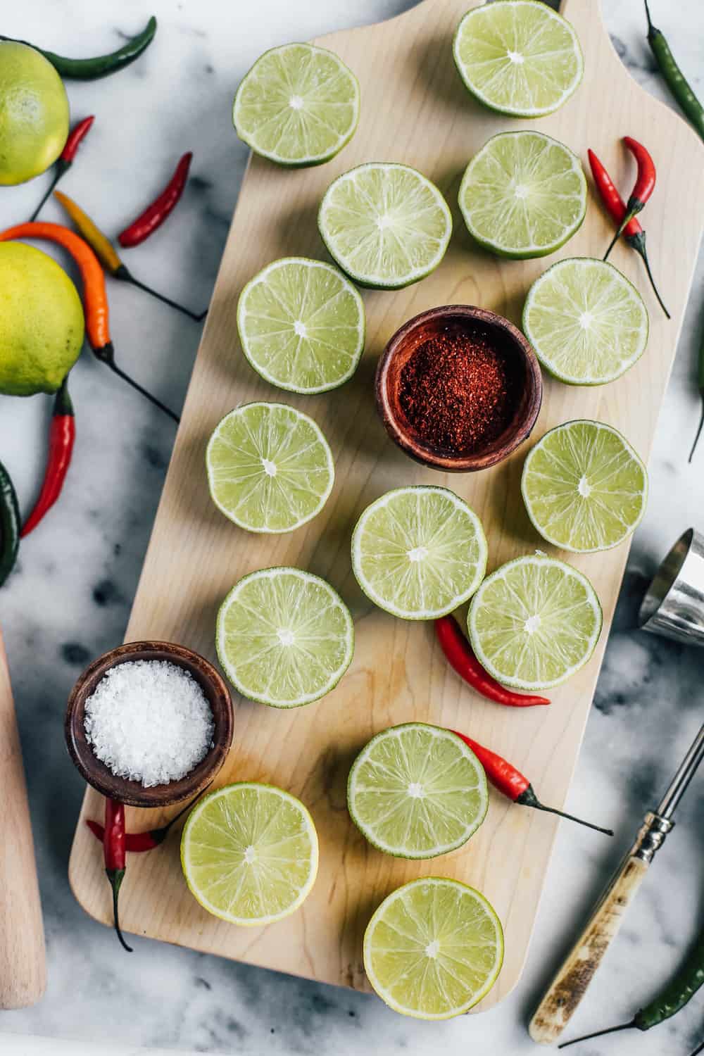 Limes cut in half with Chili and Salt on a wooden board