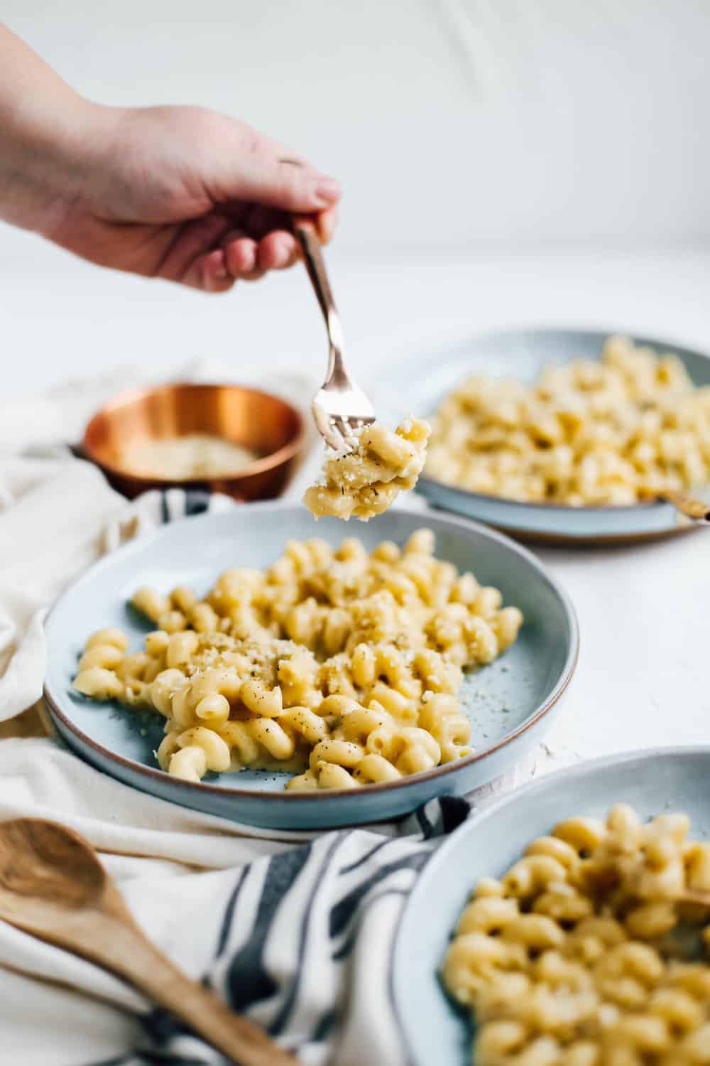 hand holding forkful of creamy chili mac and cheese on blue plate