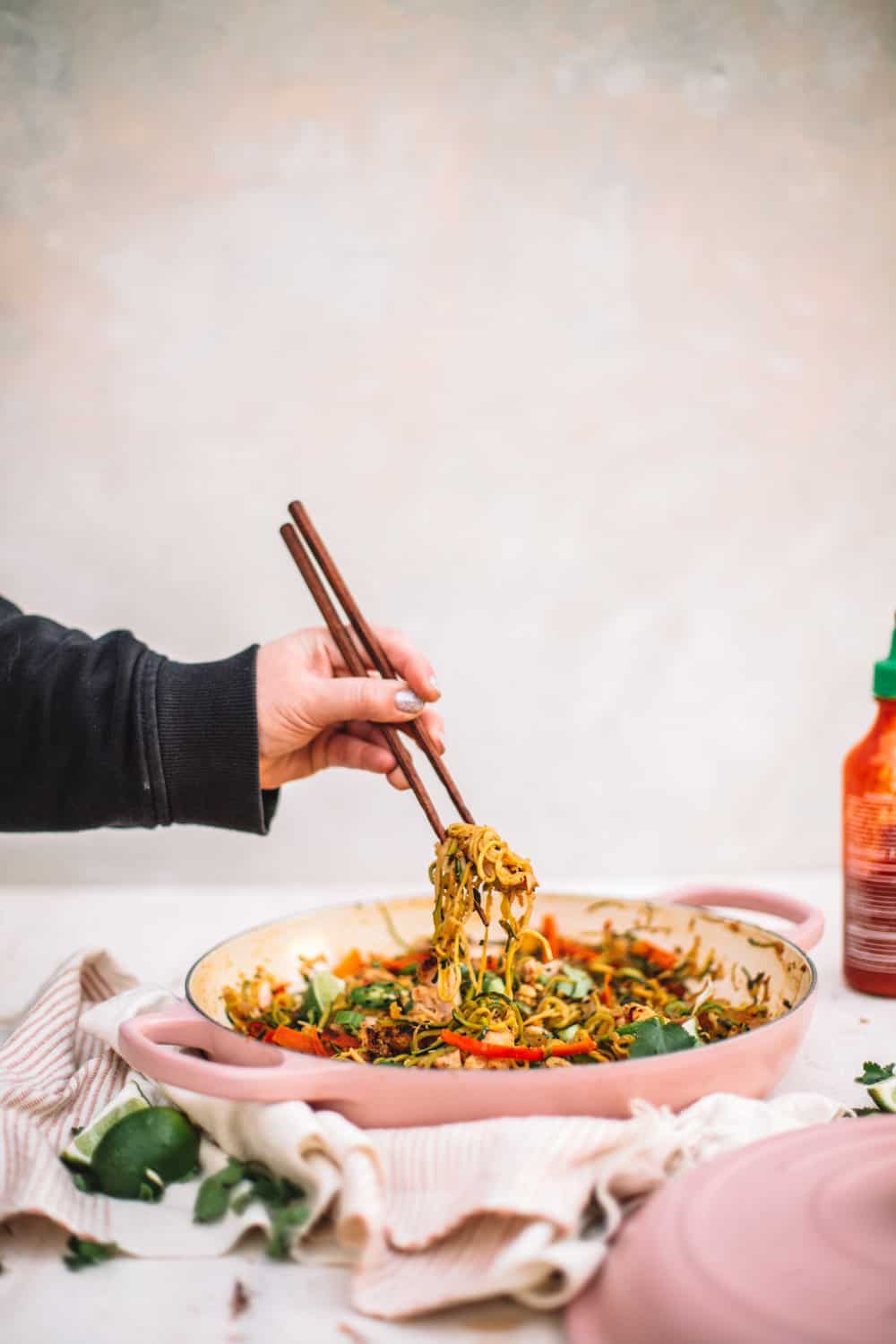 Healthy Chicken Pad Thai with Zoodles in a pan with a hand with chop sticks. 