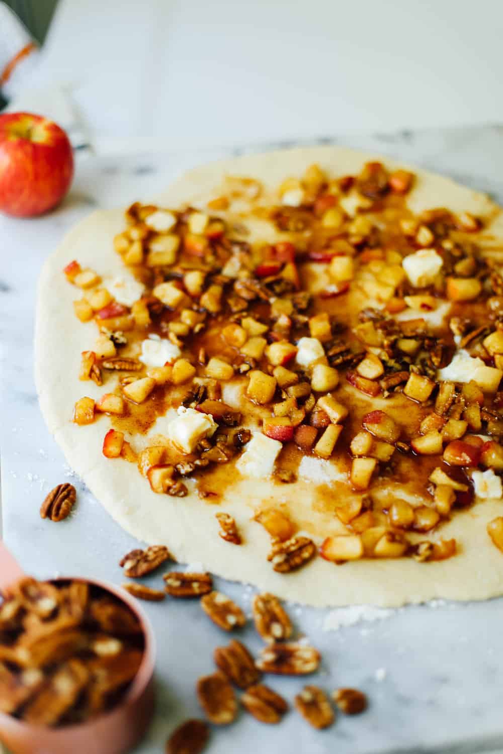 Rolled out dough with apple pecan filling on a marble board. 