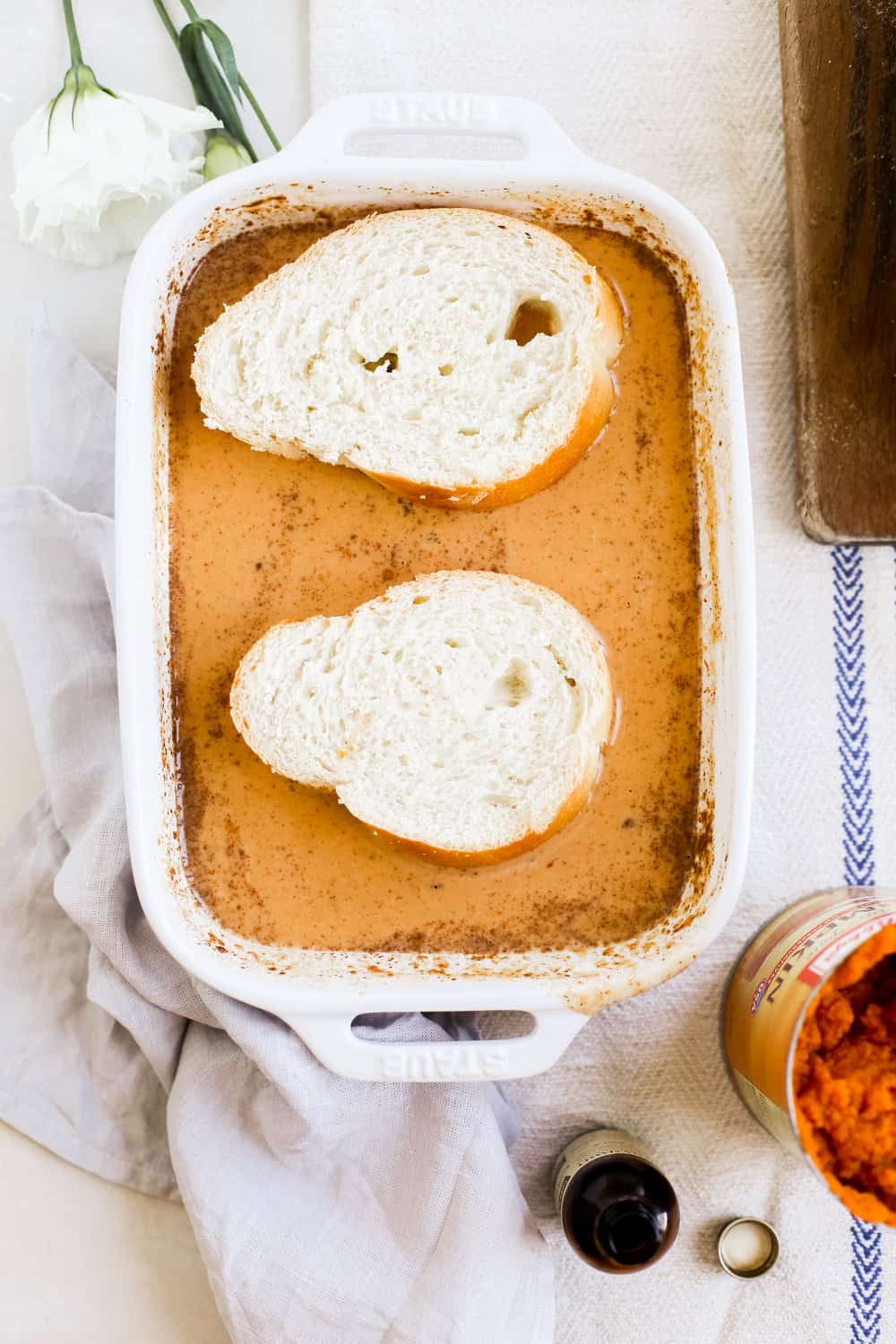 Bread in pumpkin spice egg mixture in a casserole dish. 