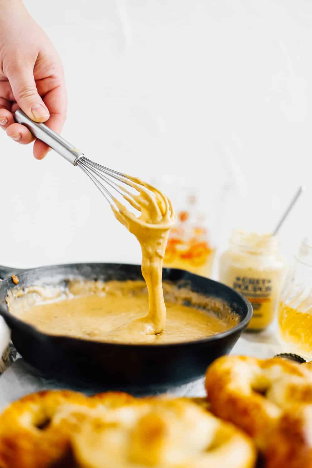 beer cheese dip in cast iron skillet with whisk