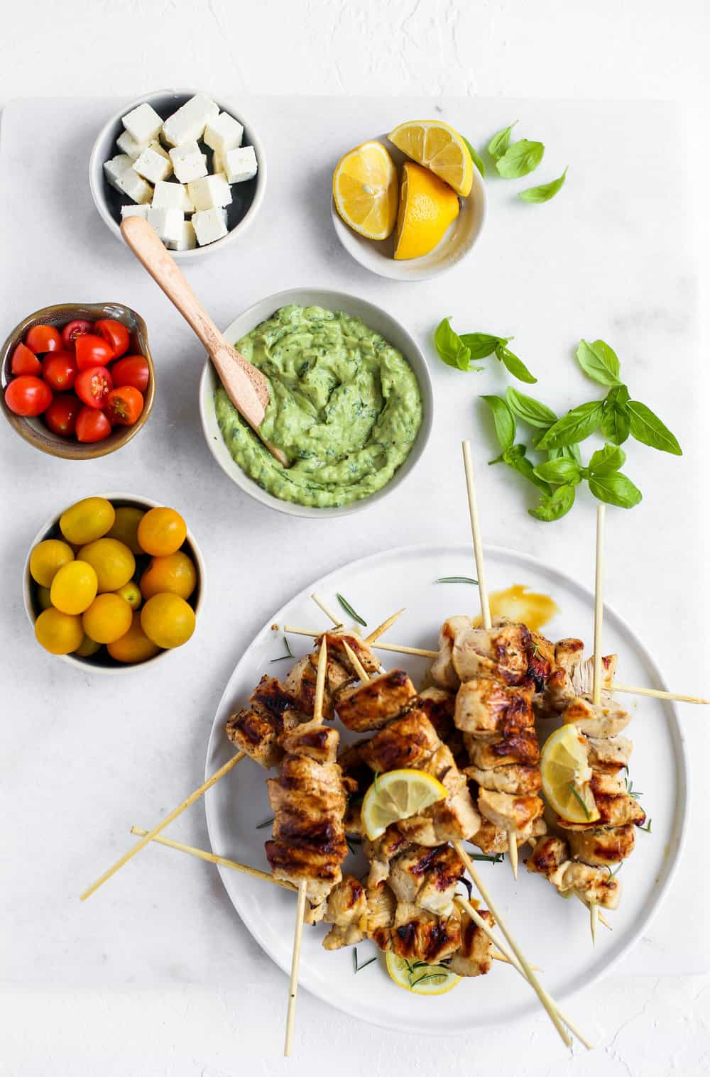 Lemon Garlic Chicken Skewer Bowls with green goddess dressing, tomatoes, feta, and lemons in a white bowl