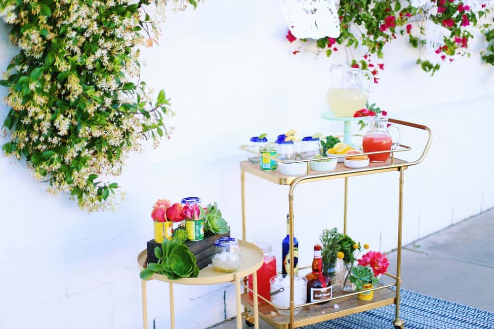 Full shot of a DIY Margarita Bar with glasses fruit wedges and pitchers of juice in front of a white backdrop