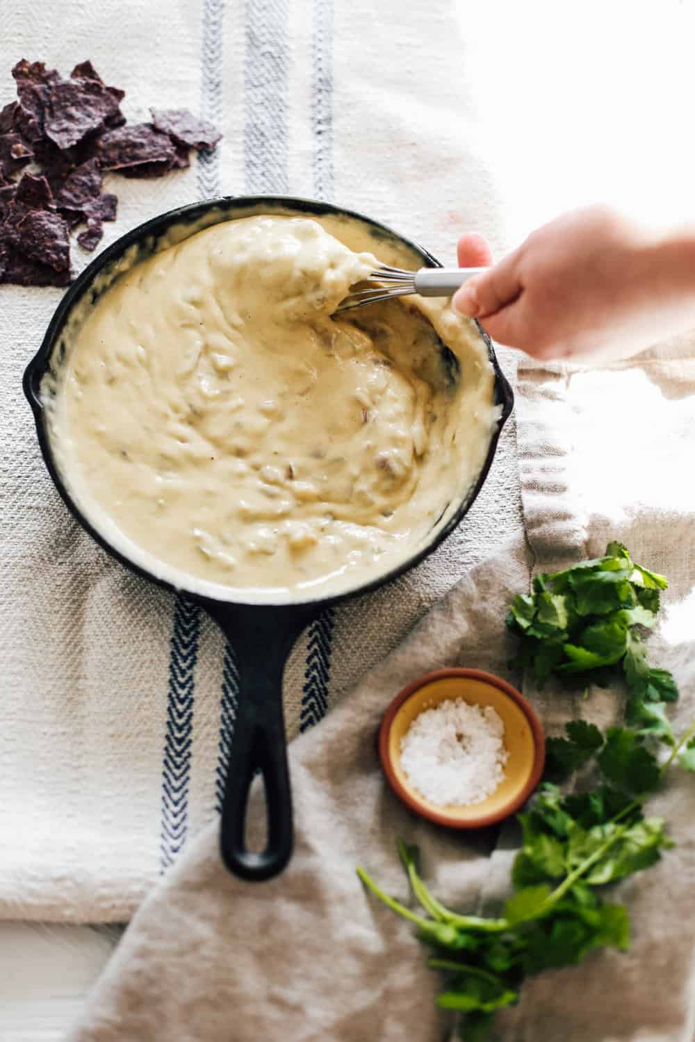 A skillet of green chile queso being whisked. 