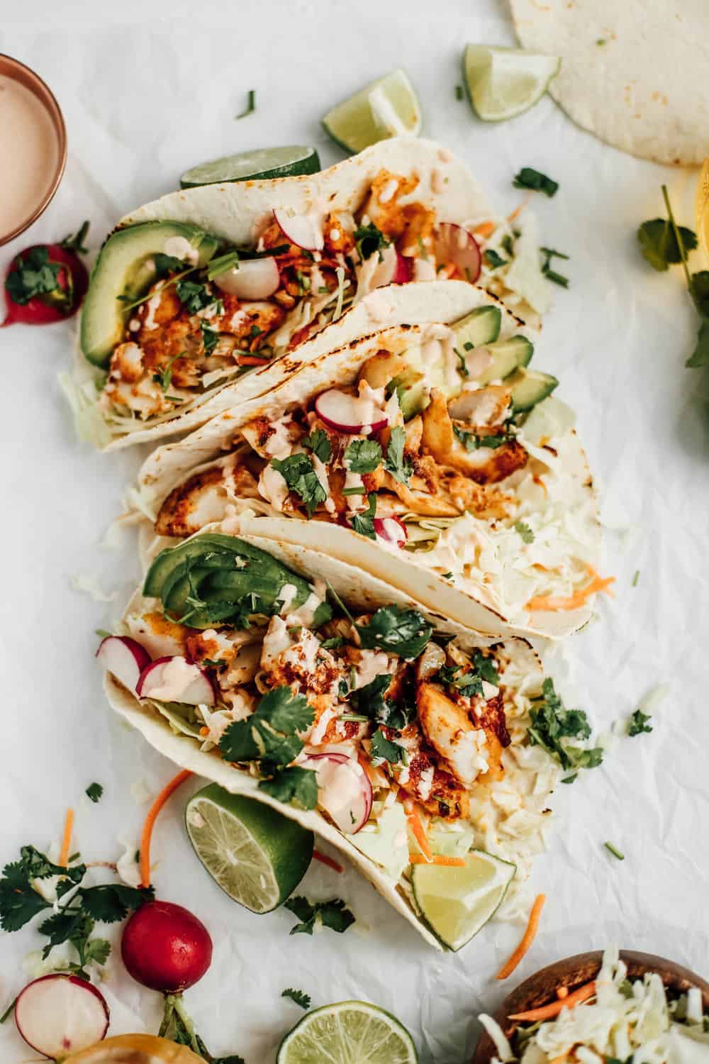 Three blackened cod tacos on wax paper.