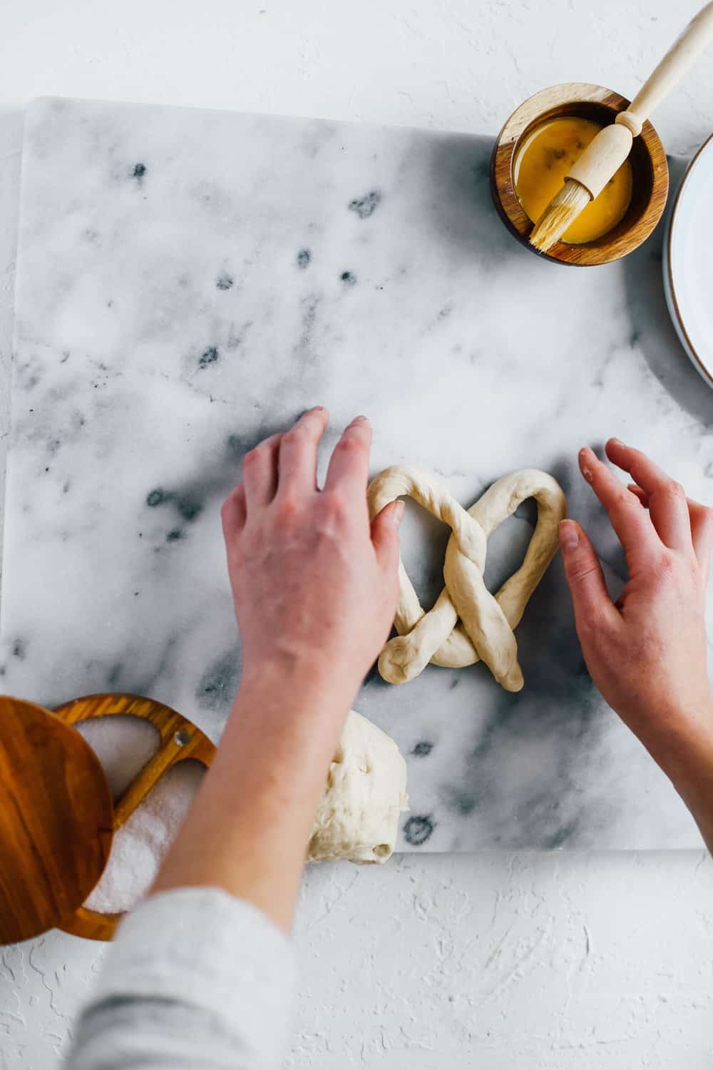 two hands shaping pretzel with dough