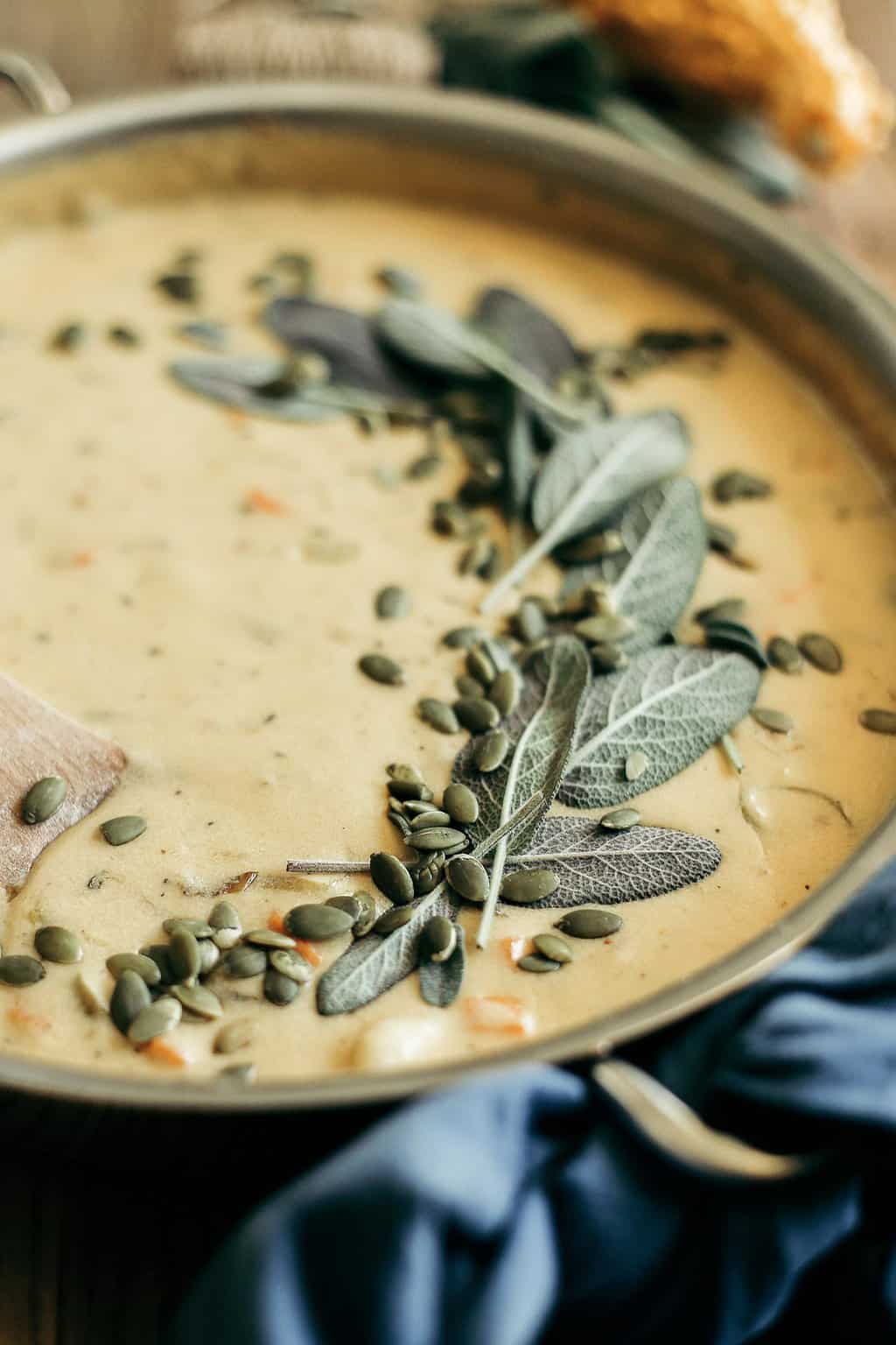 Pumpkin Beer & Sharp Cheddar Gnocchi Soup in a saute pan with sage and pepitas on top of the soup.