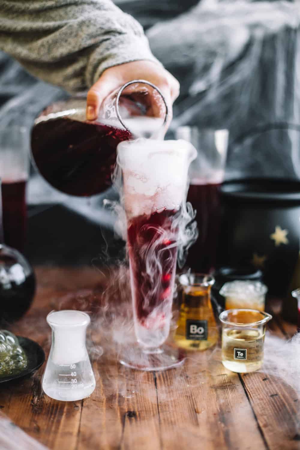 Tall glass with dry ice and Pomegranate Polyjuice Potion being poured.