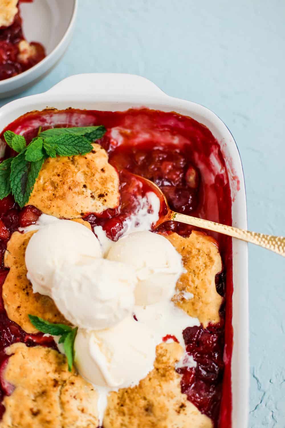 a close up photo of the vanilla ice cream covered cherry cobbler with a spoon in it