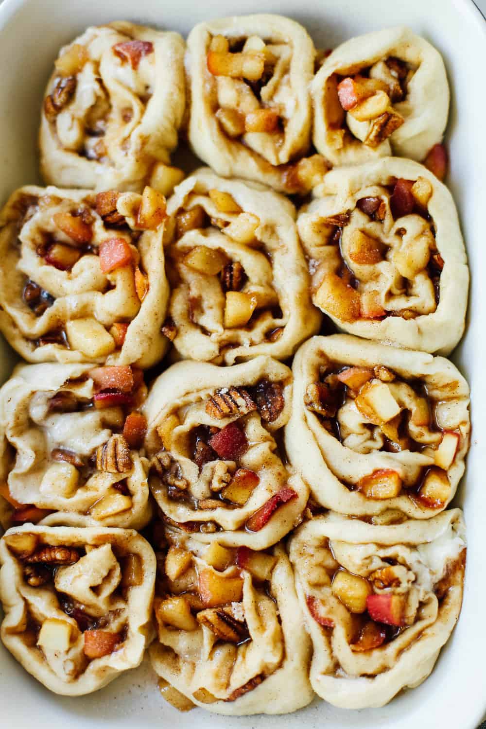 Pre baked shot of apple pecan cinnamon rolls in a casserole dish. 