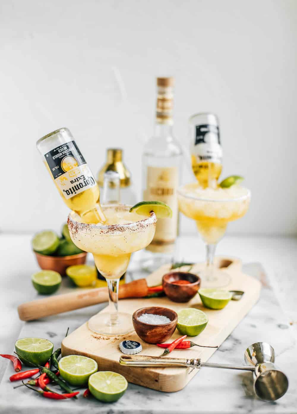 Lime and Chili Mezcal Beergaritas in glasses with Coronitas on a wooden board