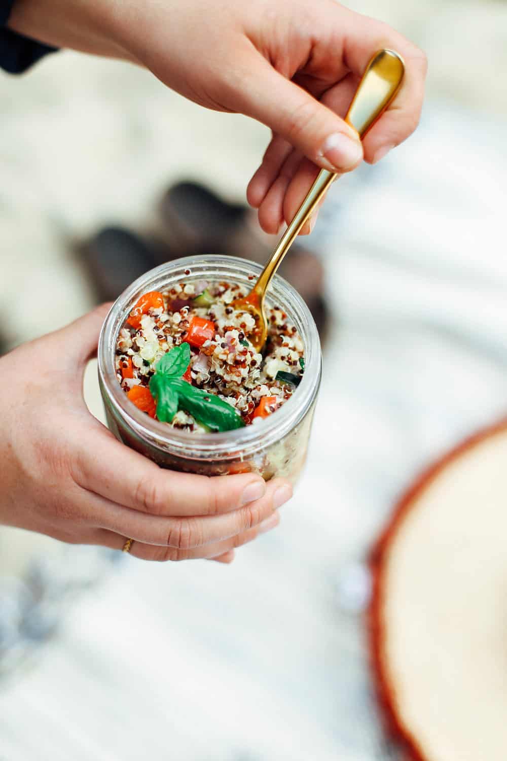 Elizabeth holding the Lemon Quinoa Side Salad in a mason jar with a gold fork