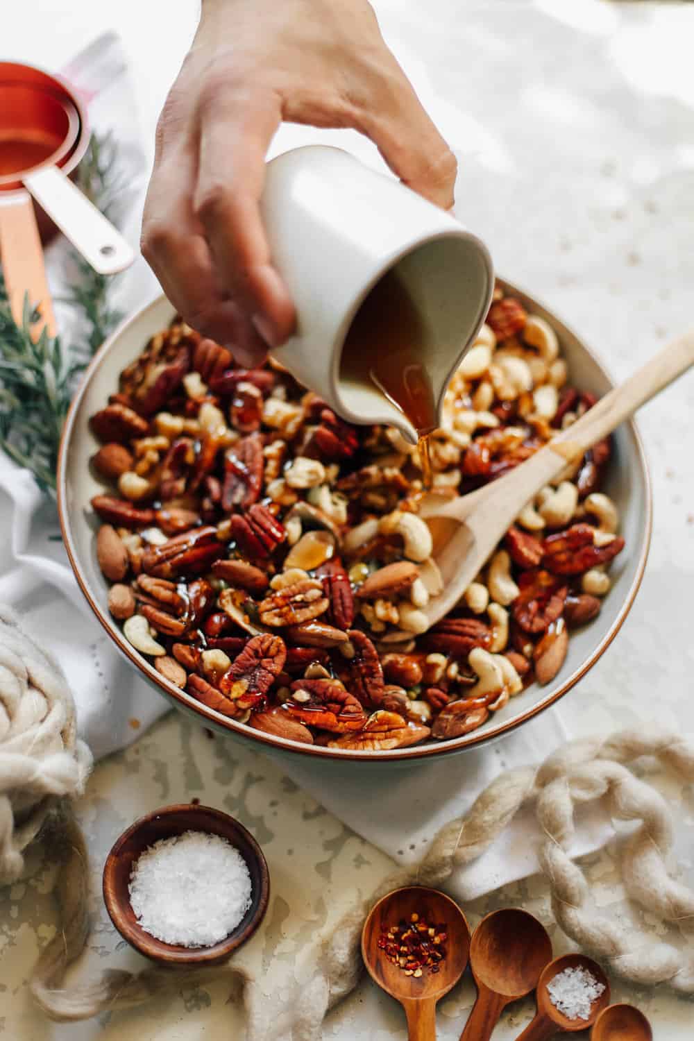 A large bowl of mixed nuts with syrup being poured. 