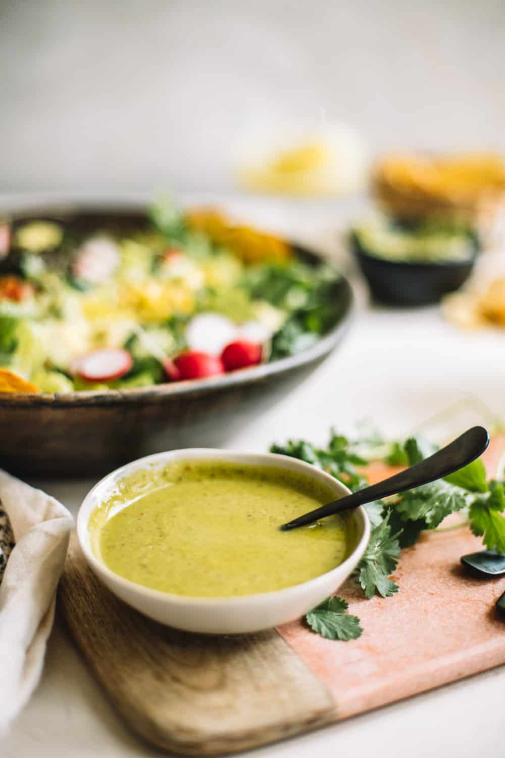 A small bowl of cilantro dressing with a black spoon. 