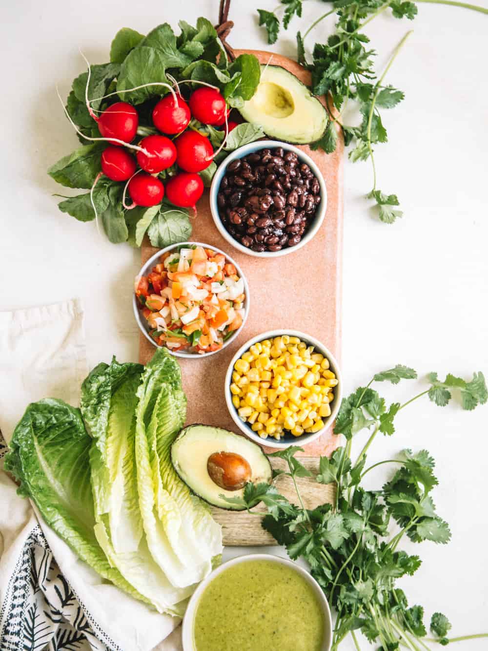 Small bowls of corn, black beans, pico de galla, radishes, and cliantro.