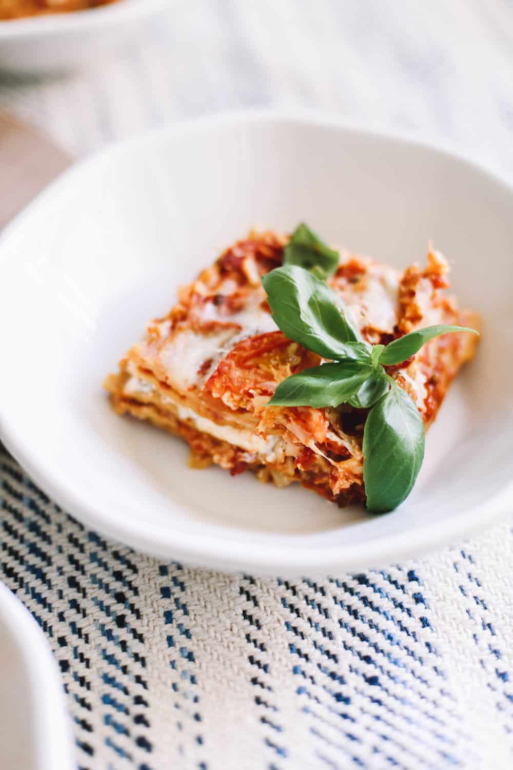 A serving of homemade lasagna in a white bowl. 