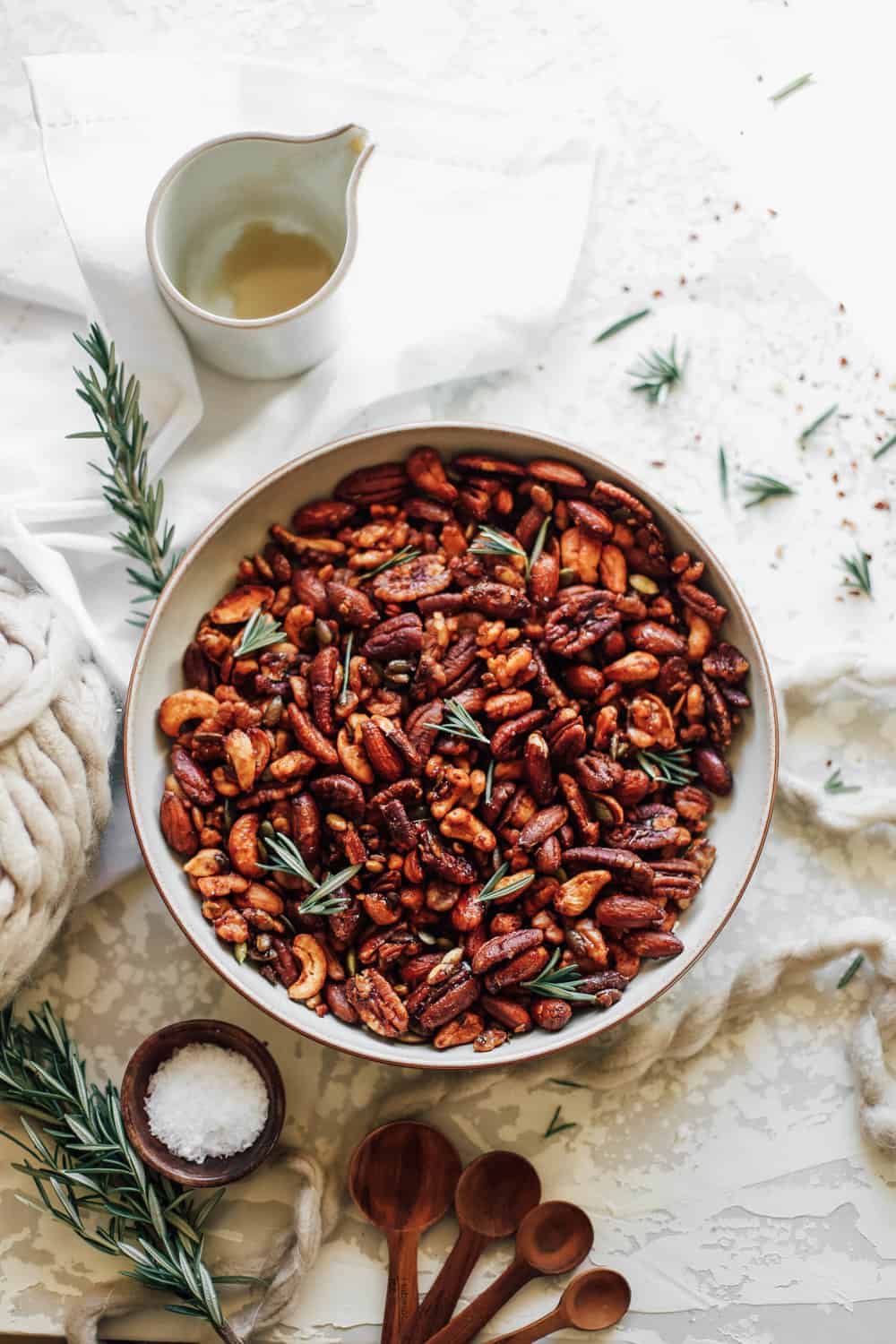 A large bowl of Sweet and Smoky Mixed Holiday Nuts with rosemary sprigs. 