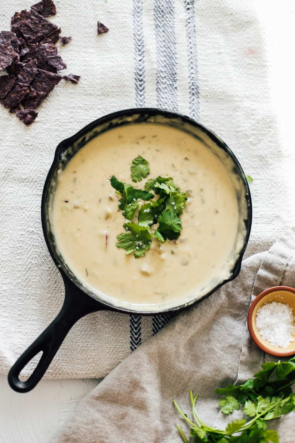 A skillet filled with green chili queso dip topped with cilantro. 