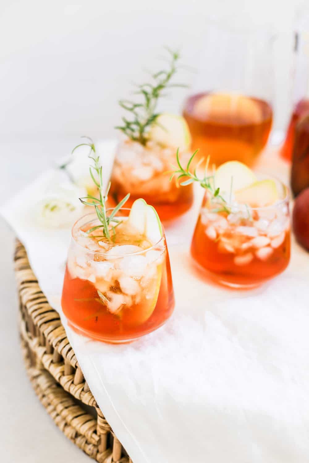 A low clear glass filled with aperol and hard cider with a rosemary sprig.