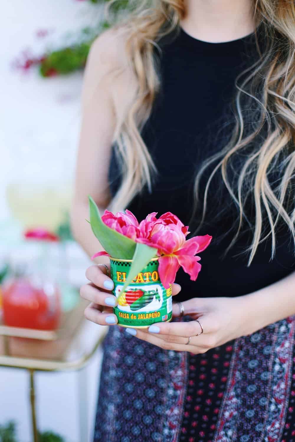 Two hands holding flowers in a Mexican food can