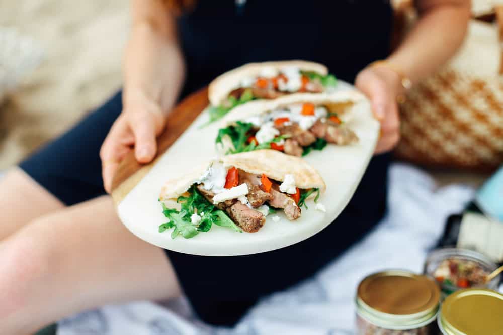 Elizabeth holding Garlic Lamb Pita Pockets with Summer Herb Slaw on a white serving board