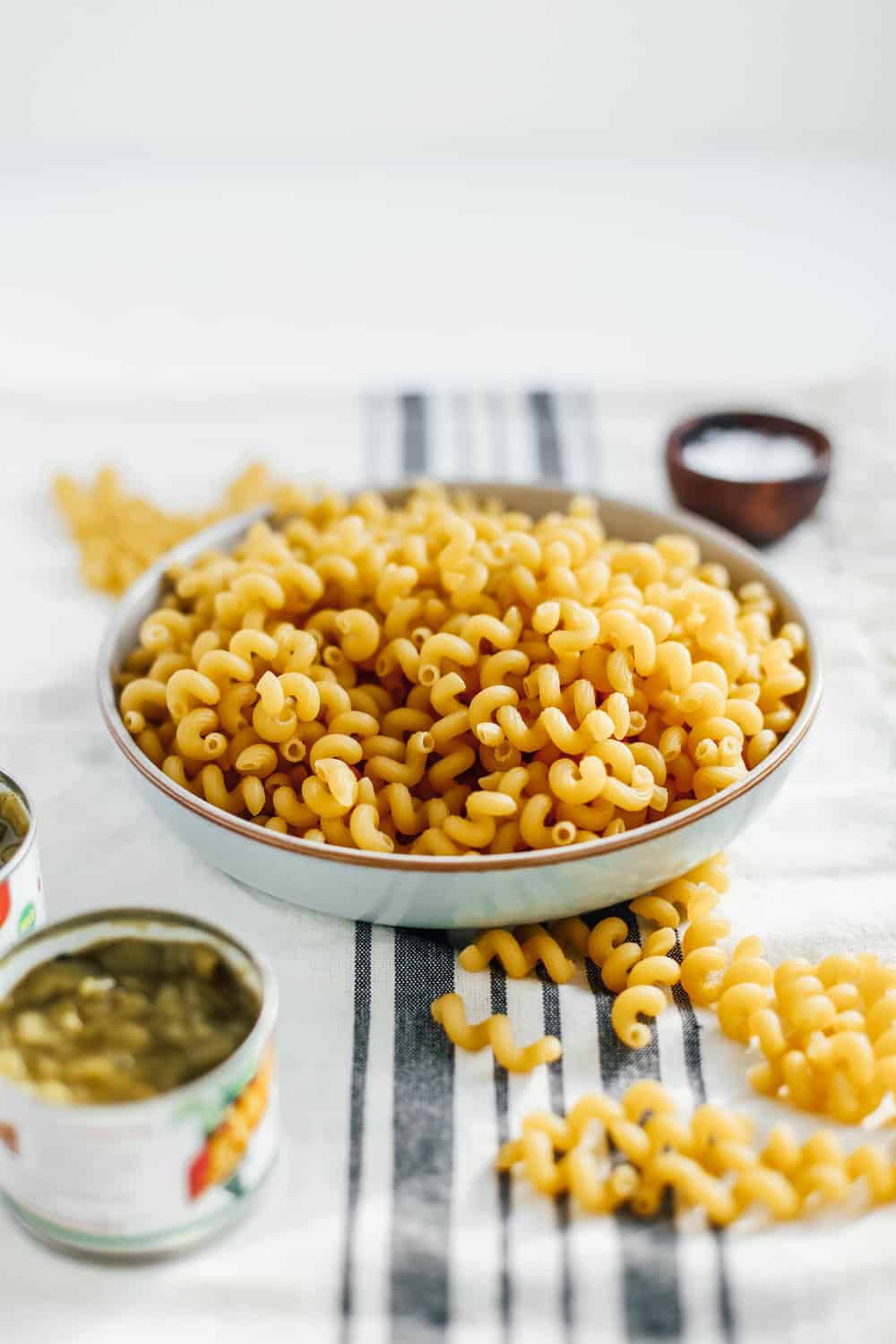 dried corkscrew pasta in white bowl with canned green chilis