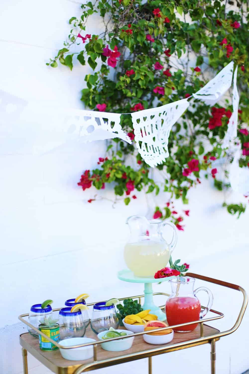 DIY Margarita Bar with juice in pitchers and margarita glasses on a bar cart