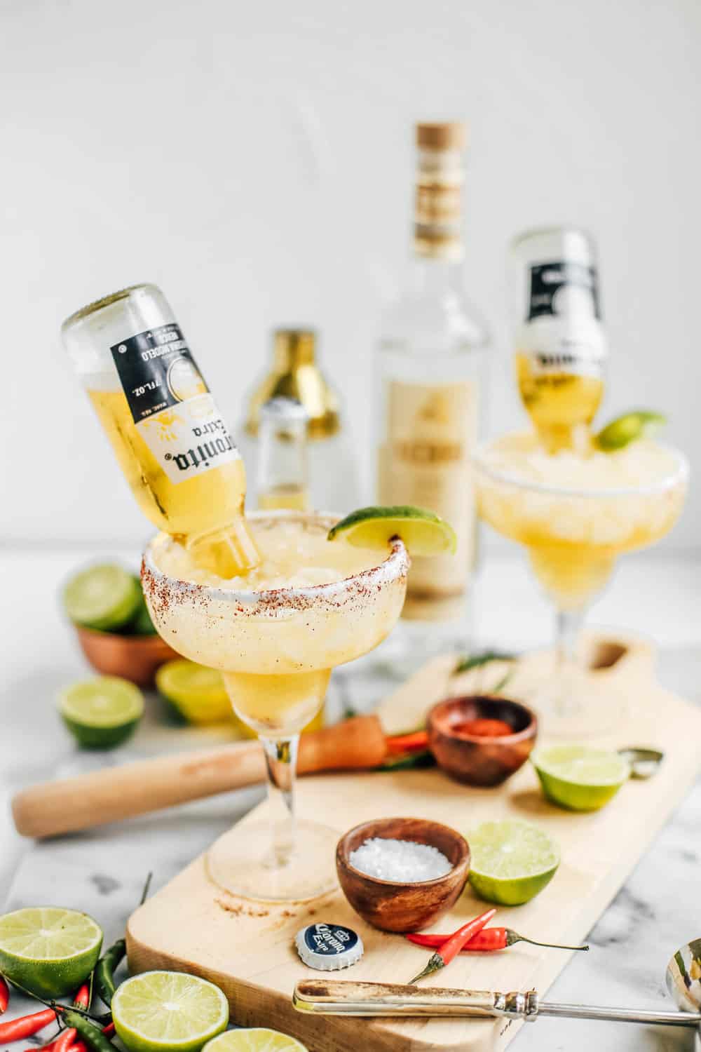 Lime and Chili Mezcal Beergaritas in glasses with Coronitas on a wooden board