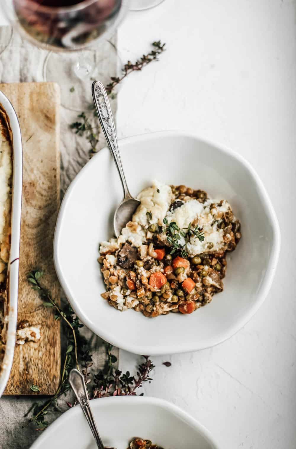 A serving of vegetarian shepherds pie in a white bowl and a silver spoon. 