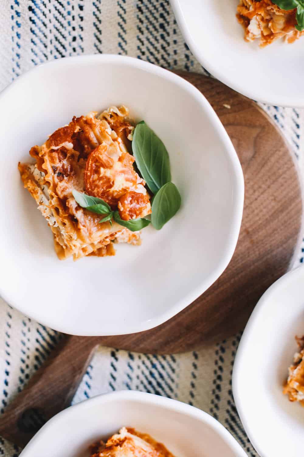 A serving of homemade lasagna in a white bowl. 