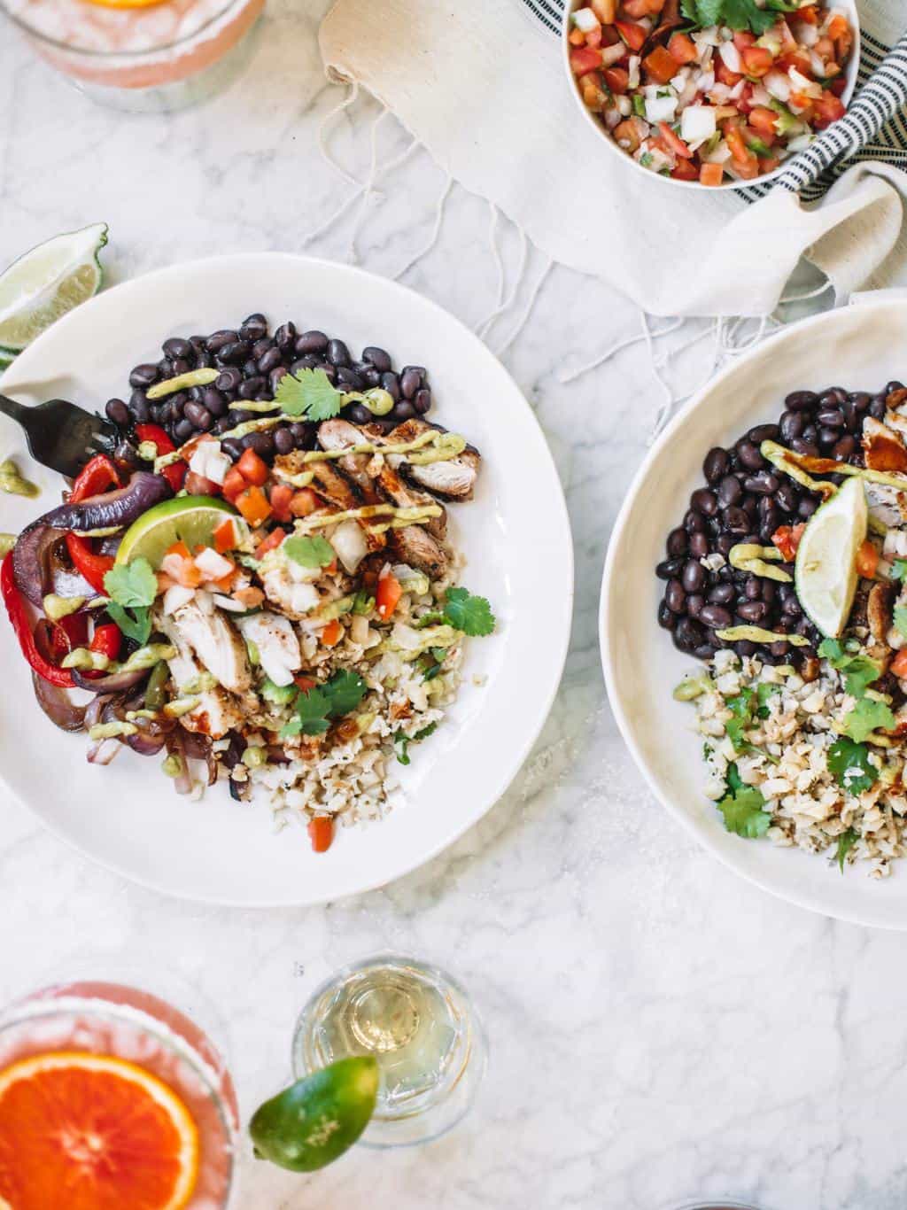 Chipotle style burrito bowls at home or for meal prep! These healthy bowls are made with cauliflower rice, juicy chicken, salsa and avocado crema!